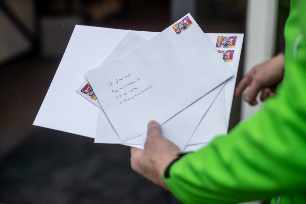 Bezorger houdt post met de Sociale Postzegel vast